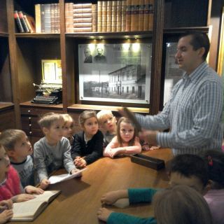 Przewodnik opowiada dzieciom o dawnej szkole.